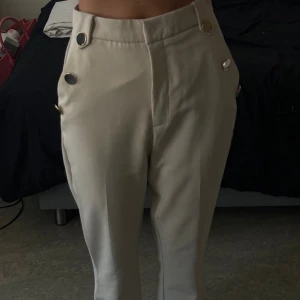 Beiga kostymbyxor  - Beiga kostymbyxor, väldigt fina och classy. Dom är dock väldigt stora på mig som ni ser. Jag är xs alltså rekommenderar jag S elr evt M. Minns ej varr de är köpta men de är i nyskick, inga skador alls.
