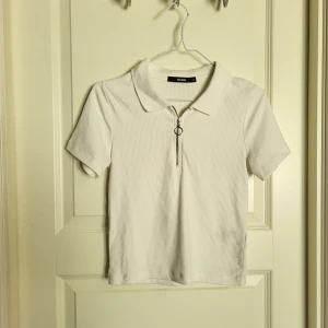 T-shirt mes dragkedja - En vit tshirt med dragkedja och krage från bikbok. Använd fåtal gånger och är i fint skick!