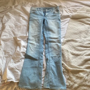 Ljusa bootcut jeans från H&M - Säljer ett par ljusa low waist bootcut jeans från H&M. De har en justerbar låg midja och är i en snygg ljusblå färg. 