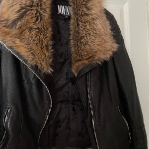 Svart skinnjacka med pälsdetaljer från Jofama - Säljer en snygg svart skinnjacka från Jofama by Kenza i storlek 38. Jackan har en cool pälsdetalj runt kragen och dragkedjor på sidorna. Den har också spännen i midjan för en justerbar passform. Perfekt för höst och vinter!