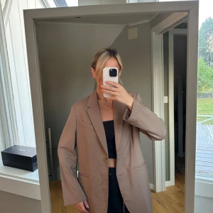 Beige kavaj - Säljer en snygg beige kavaj med klassisk design. Den har långa ärmar och två knappar framtill. Perfekt för både vardag och fest! 🕺