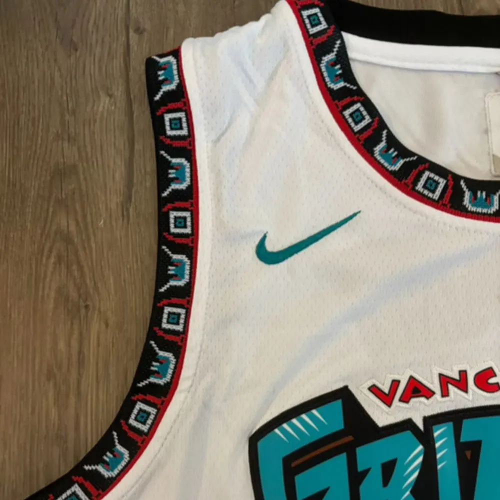 Säljer ett sjukt snyggt Vancouver Grizzlies basketlinne från Nike. Det är vitt med coola turkosa och svarta detaljer. Har nummer 12 och namnet 'Morant' på baksidan. Perfekt för basketfans eller som en stilren streetwear-look!. Sportswear.