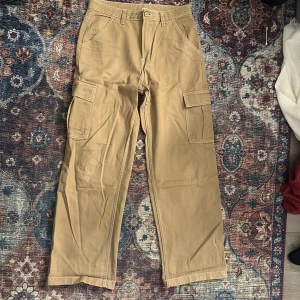 Beige cargobyxor från H&M Divided - Säljer ett par beige cargobyxor från H&M Divided. Byxorna har flera fickor och är i mycket bra skick, lik ett par nya. De har en baggy/loose passform och är i storlek 40.