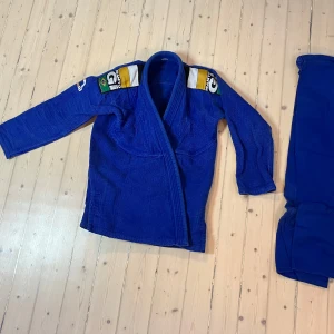 Blå BJJ Gi från Manto A2 - Säljer en blå BJJ Gi från Manto storlek A2 (175-179 cm lagom) med broderade detaljer på axlarna. Perfekt för träning och tävling. Gi:n har en traditionell passform och är tillverkad i slitstarkt material. Manto är bland de bättre å passar utmärkt för någon som vill pröva på BJJ under en första termin med tanke på hur dyra terminsavgifterna blivit nu! Eller som en extra dräkt under läger med långa dagar då man är i behov av ett fräsht ombyte! Pris kan diskuteras vid snabb affär, skriv!
