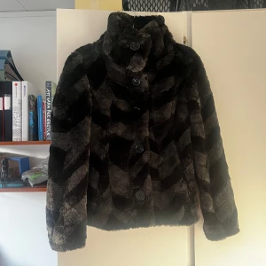 Svart pälsjacka  - En jättefin svart pälsjacka från Vila med ett snyggt men lite diskret mönster. Jackan har långa ärmar och knappar framtill. Nästan aldrig använd💕