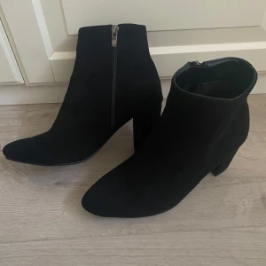 Svarta stövletter med dragkedja - Snygga svarta stövletter i mocka med dragkedja på sidan. De har en spetsig tå och en bekväm klack, perfekta för både vardag och festliga tillfällen. Aldig använda!