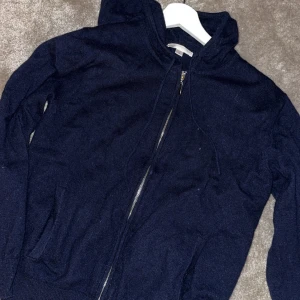 Kashmir zip tröja - Säljer en mörkblå stickad hoodie med dragkedja och huva. Perfekt för kyliga dagar. Den har långa ärmar och en bekväm passform.