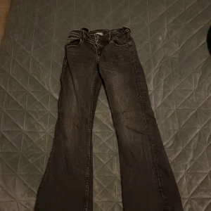 Grå/Svarta bootcut jeans - Snygga svarta bootcut jeans med klassisk femficksdesign och knappgylf. Man kan typ ha dom till allt och dom är jätte snygga 🥰 