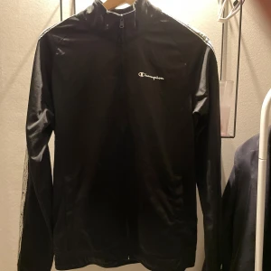 Svart jacka från Champion - Säljer en svart jacka från Champion med dragkedja hela vägen, användt lite grann! Perfekt för träning eller bara använda till vardags, har även matchande byxor till.