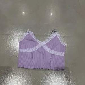 Lila ribbad topp från H&M - Säljer en söt lila ribbad topp från H&M med spetsdetaljer. Toppen har en omlott-design och justerbara axelband. Skriv privat för fler bilder eller frågor :) 