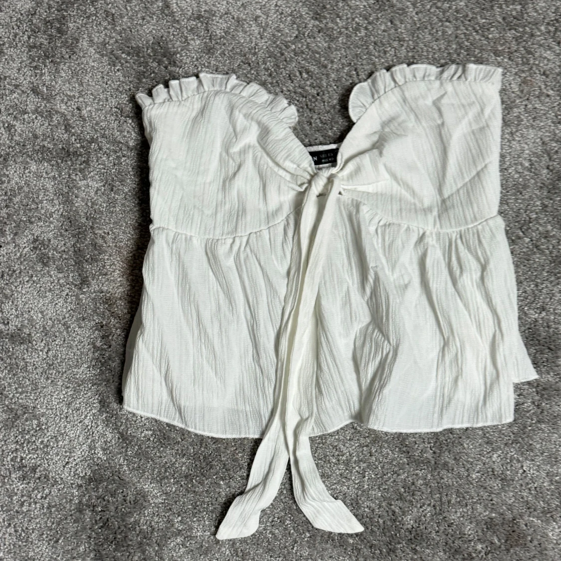 Vit axelbandslös topp med volang