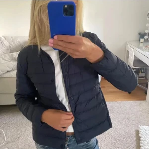 Uniqlo jacka - Snygg svart pufferjacka med knappar framtill. Perfekt för kyligare dagar och enkel att matcha med olika outfits. Jackan har en stilren design och är ett måste i garderoben.