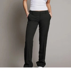 Svarta kostymbyxor - Snygga svarta kostymbyxor med normal passform och låg midja. Byxorna har en klassisk design med dragkedja och knappar framtill. Perfekta för en stilren look. Köpta för 500kr på Bikbok i modellen Vera! Byxorna är i bra skick och även dessa är uppsydda så de ska passa mig som är 165 cm lång! 