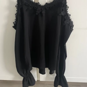 Svart offshoulder blus från Gina Tricot - Jätte fin  svart offshoulder blus från Gina Tricot med spetsdetaljer längs halsringningen. Toppen har långa ärmar och smala axelband. Den har inga defekter förutom att lappen lossnat lite som man ser på sista bilden💕finns inte på hemsidan längre, pris kan diskuteras