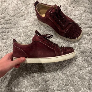 Vinröda Louboutins - - Vinröda louboutin skor - Skick 8/10 (använda men inga skador alla spikar kvar) - Storlek 41 passar 41-42 - endast skorna medföljer