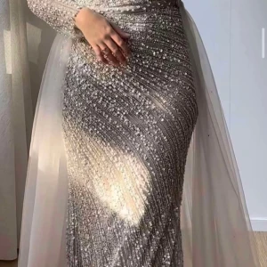 Glittrig långklänning med paljetter - Elegant långklänning i silver med glittrande paljetter och långa ärmar. Klänningen har en figurnära passform och ett avtagbart släp. Storlek 40/42. Nypriset var 7800 från Sashas i Södertälje. Säljs nu för 3000! Men pris går att diskutera. Finns i Dalarna eller Stockholm men kan fraktas. 