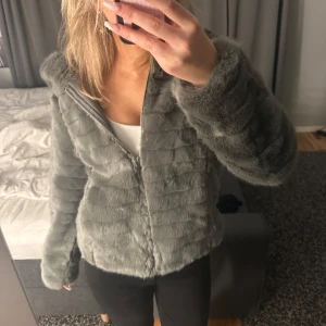 Grå pälsjacka  - Mysig grå pälsjacka från Fascinate med dragkedja och huva. Strl M🩷🩷