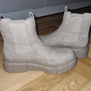 Beige boots i mocka - Snygga beige boots i mocka med grov sula och elastiska paneler för enkel på- och avtagning. Perfekta för en stilren look.