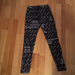 Träningsbyxor från Reebok - Snygga svarta träningsbyxor från Reebok med vitt logotypmönster. De har en tight passform. 