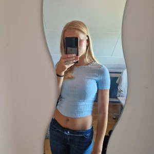 Ljusblå topp med knytrygg - Snygga ljusblå ribbad t-shirt med knytning i ryggen. Köparen står för frakten.