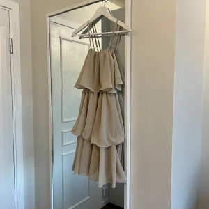 Beige volangklänning - Beige klänning med flera lager volanger och smala axelband. Använd två gånger, storlek S