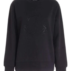 Svart sweatshirt från Moncler - Snygg svart sweatshirt från Moncler med diskret broderad logga på bröstet. Tröjan har en klassisk passform med långa ärmar och ribbade muddar vid ärmslut och nederkant. Perfekt för en stilren och bekväm look.