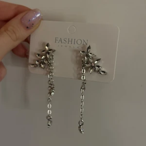 Silvriga örhängen med blommor och kedjor - Eleganta silvriga örhängen med blommotiv och hängande kedjor. Super fina men har tyvärr aldrig kommit till användning 🫶🏼