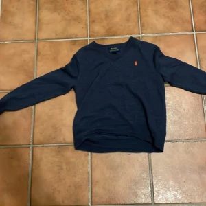 Mörkblå tröja från Polo Ralph Lauren - Säljer en stilren mörkblå tröja från Polo Ralph Lauren, perfekt för en avslappnad men snygg look. Har dock krympt i tvätten däravpriset. 