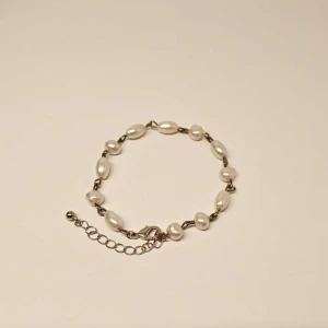 Armband med vita pärlor - Elegant armband med vita pärlor och en justerbar kedja. Perfekt för att ge en sofistikerad touch till din stil. Pärlorna är jämnt fördelade och kedjan har en enkel låsning. Handgjort av oss på Dahlia UF🌸