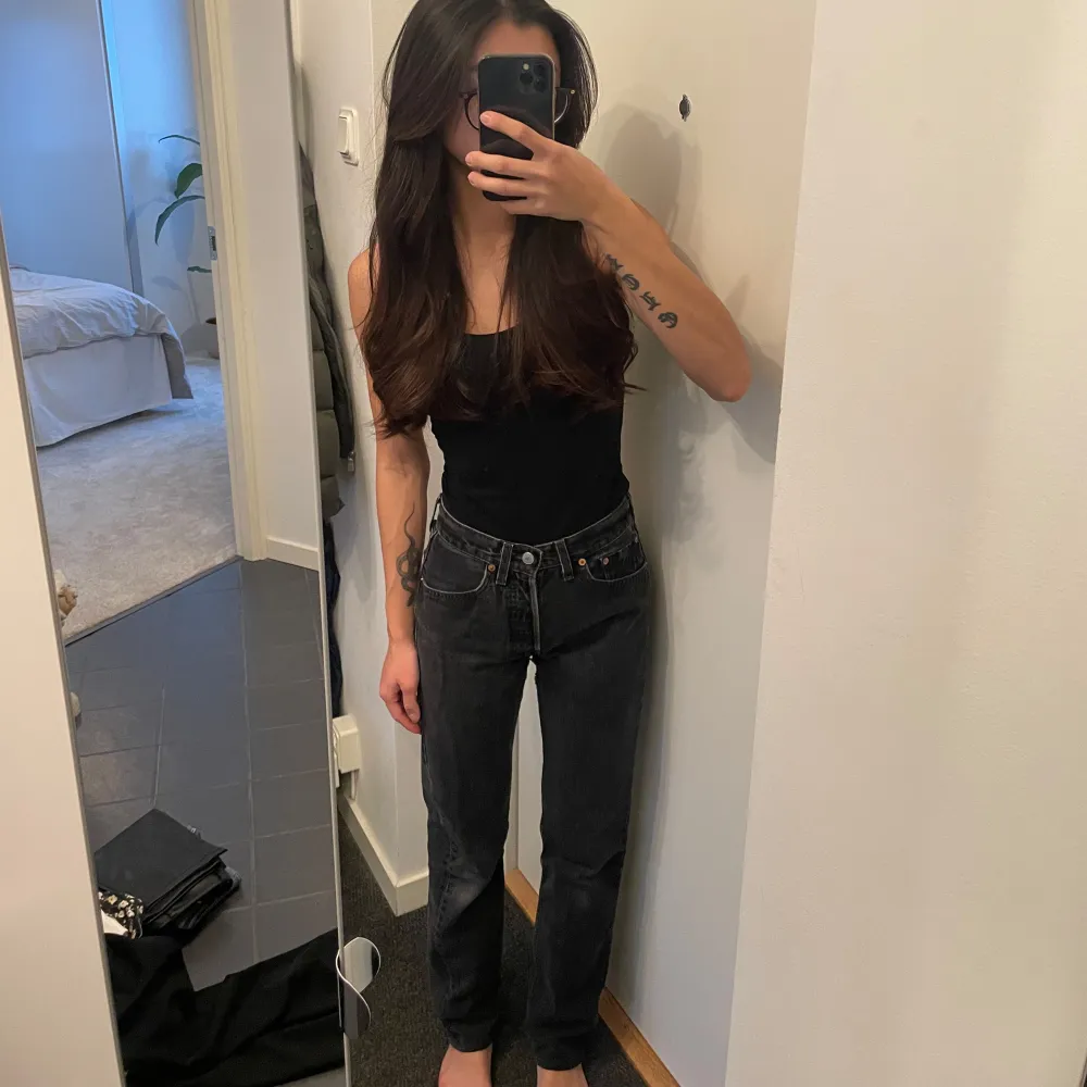 Snygga gråa Levis jeans med mid midja och modellen 501 Strl w26 och är uppsydda för mig som är 164 cm lång. De är köpta second hand och har slitage på sin färg men jag tycker att de gör jeansen ännu snyggare. Finns slitage mellan låren men det är lagat så inga hål eller liknande finns på de.. Farkut & Housut.