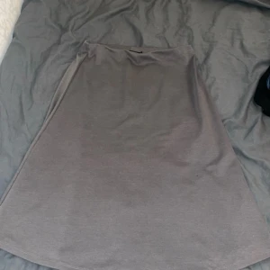 Brun/grå kjol - Snygg brun/grå kjol i en klassisk design. Perfekt för en stilren look. Kjolen har en enkel och elegant form som passar till många olika tillfällen.