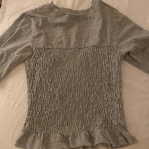 Grå topp hm - Säljer en grå blus från HM med trekvartsärmar. Perfekt för en stilren look!