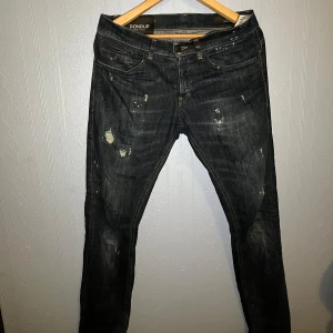 Dondup george  - Säljer ett par mörkblå skinny fit jeans från Dondup. De har en sliten look med små revor och slitningar för en trendig stil. Perfekta för en casual outfit. Sitter som w30