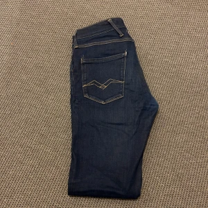 Replay jeans - Snygga mörkblå jeans med kontrastsömmar och klassisk femficksdesign. Byxorna har en slim passform och är perfekta för en avslappnad stil. De har en knapp- och dragkedjestängning framtill. För minsta fundering, hör av dig👍🏻