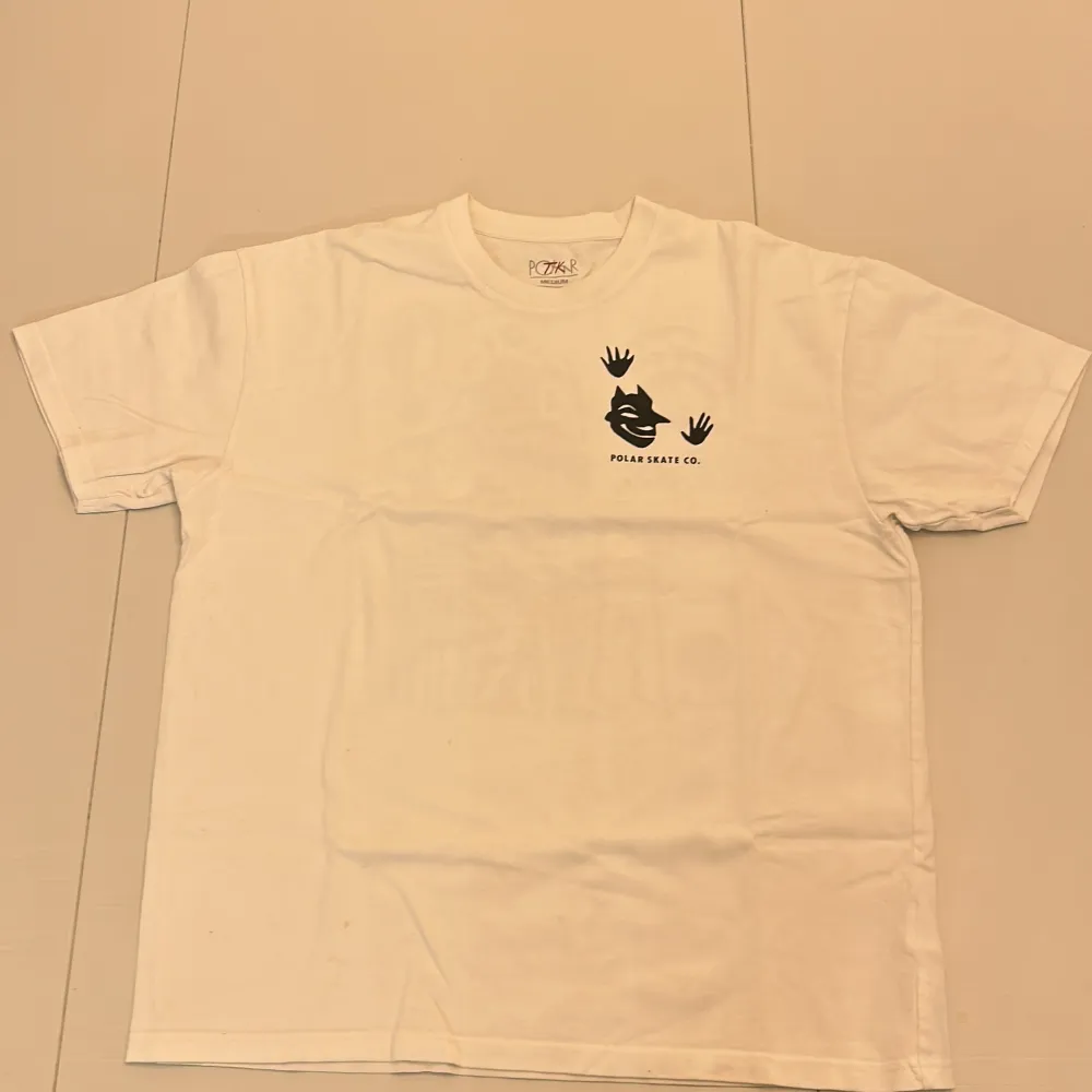 Säljer en vit t-shirt från Polar Skate Co. med ett unikt svart tryck på både fram- och baksidan. T-shirten har korta ärmar och är i normal passform. Har några små fläckar. Skriv om ni har frågor. T-paidat.
