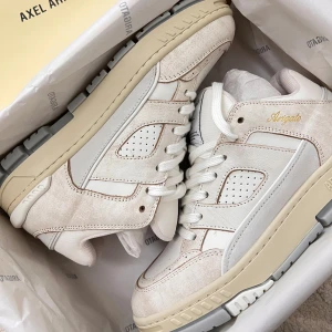 Sneakers från Axel Arigato - Helt nya sneakers från Axel Arigato i en stilren kombination av beige och vit. Skorna har snörning och en robust sula som ger bra komfort. Perfekta för en trendig vardagslook.                             - Orginal boxen                                                             - 1st Orginal Axel Arogato bag                                    Följer med skorna!❤️ 
