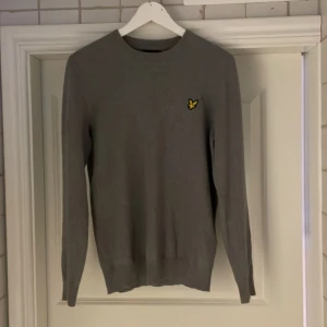 Grå tröja från Lyle & Scott - Säljer en stilren grå tröja från Lyle & Scott. Tröjan har långa ärmar och en rund halsringning. 