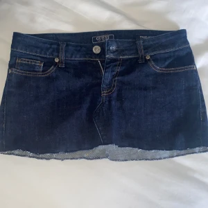 Mörkblå jeanskjol från Guess - Snygg mörkblå jeanskjol från Guess med rå kant. Omsydd från ett par jeans och är lågmidjade. Ungefär storlek S