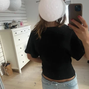 Svart kortärmad topp - Säljer en stilren svart kortärmad topp med mycket fin passform. Perfekt för en stilren look. Toppen är enkel och mångsidig, lätt att matcha med olika outfits.
