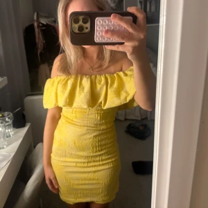 Gul offshoulder klänning - Säljer en söt gul offshoulder klänning med volangdetaljer. Klänningen har en tight passform och man kan ha den på tre olika sätt antingen helt off shoulder eller one shoulder eller ha den över båda armarna. Väldigt söt och gul aldrig använd 