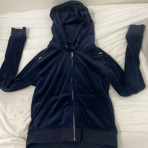 Mörkblå hoodie med dragkedja - Säljer en snygg mörkblå hoodie från Juicy Couture i mjukt material. Den har en dragkedja framtill och en skön huva. Perfekt för en avslappnad stil.