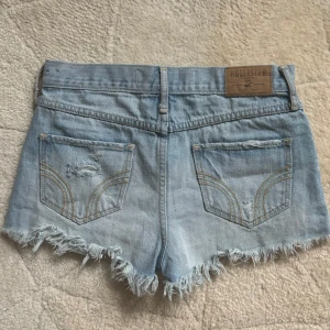 Ljusa jeansshorts från Hollister - Säljer ett par ljusa jeansshorts från Hollister med slitna detaljer och fransig kant. Säljer dem för att de är för små på mig. Passar xxs-xs. Midjemåttet rakt över är 34-35cm 