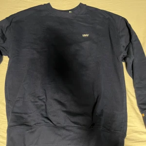 Mörkblå sweatshirt från Levi's - Säljer en stilren mörkblå sweatshirt från Levi's Gold Tab-kollektion. Tröjan har en klassisk rund hals och långa ärmar. Perfekt för en avslappnad look. Levi's logga är diskret placerad på bröstet.