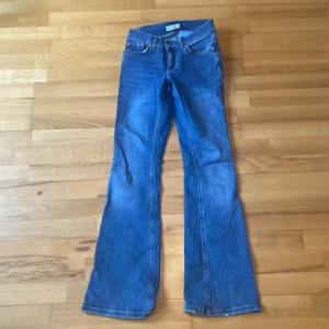 Blå bootcut jeans från Perfect Jeans - Säljer ett par klassiska blå bootcut jeans från Gina tricot. De har en snygg passform med låg midja och är perfekta för en avslappnad stil. Jeansen har en knapp och dragkedja framtill samt fickor både fram och bak.