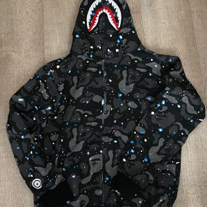 Bape hoodie  -  "Säljer en äkta Bape hoodie i svart, storlek M. Mycket bra skick, sparsamt använd. Perfekt för dig som gillar streetwear! Kan mötas upp eller skickas. Hör av dig vid frågor!"  