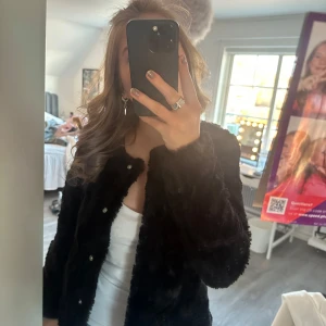 Svart pälsjacka från Vero Moda - Säljer en snygg svart pälsjacka från Vero Moda. Jackan har en mjuk och fluffig yta med knappar framtill. Perfekt för att hålla sig varm och stilren under kyliga dagar. 🖤