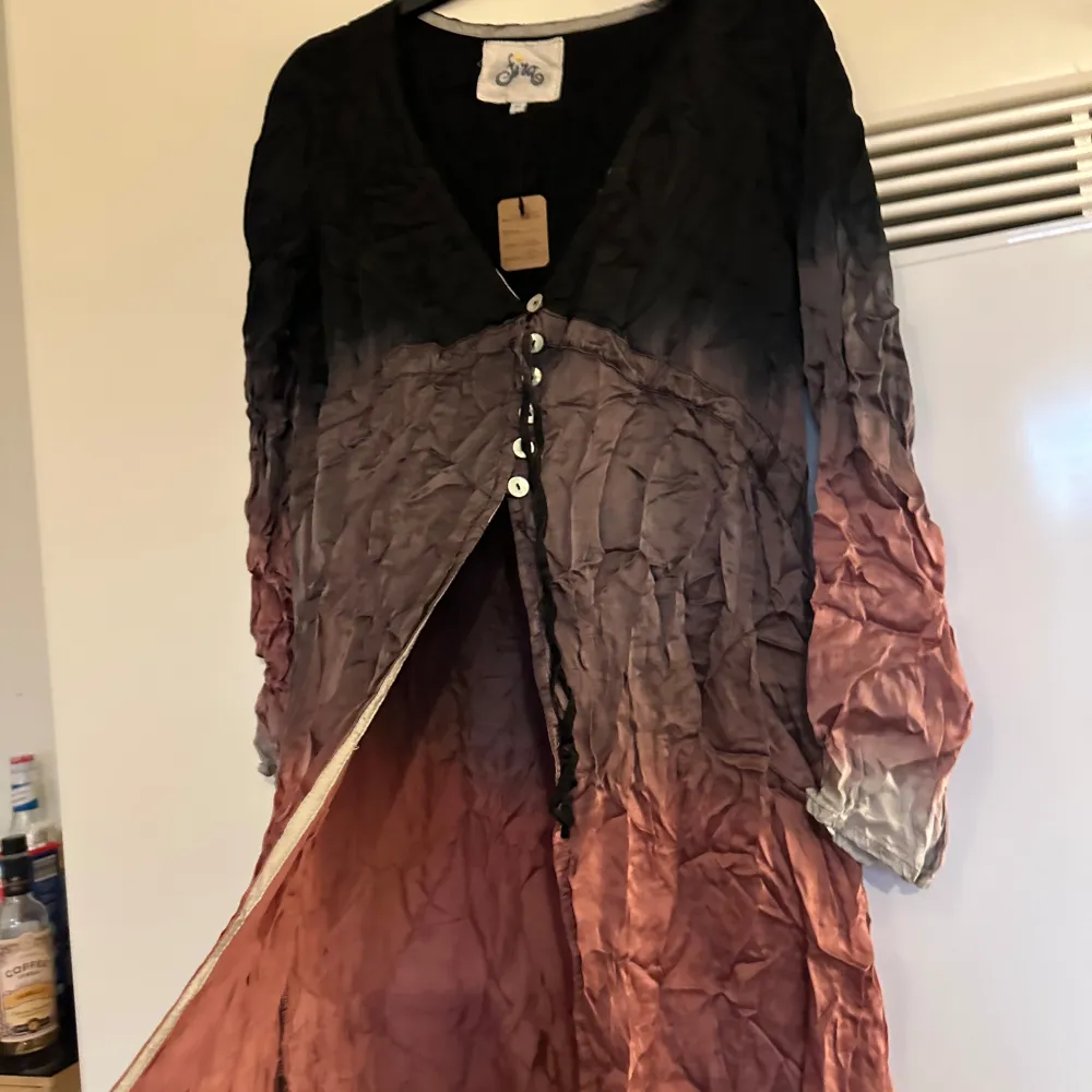 Säljer en unik flerfärgad klänning/ cardigan med knappar framtill. Klänningen har en ombre-effekt i svart, brun och grå nyans. Den är långärmad och har en avslappnad passform. Perfekt för en bohemisk look! Från märket Fira i storlek XS men passar en XS/S. Mycket fint skick, men skulle behöva strykas. . Mekot.