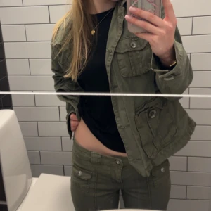 Olivgröna byxor med fickdetaljer - Snygga olivgröna byxor med låg midja och praktiska fickor framtill. Byxorna har en bootcut-stil som ger en avslappnad look. Perfekta för en casual outfit. Byxorna är från H&M och dom är storlek 36💞