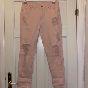 jeans med slitningar - Ljusrosa jeans med slitningar på framsidan. De har en klassisk femficksdesign och är lite lösa i modellen. Perfekta för en avslappnad stil.