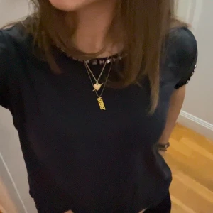 Svart topp med nitar - Säljer en svart topp med korta ärmar och dekorativa nitar runt halsringningen och ärmarna🩷